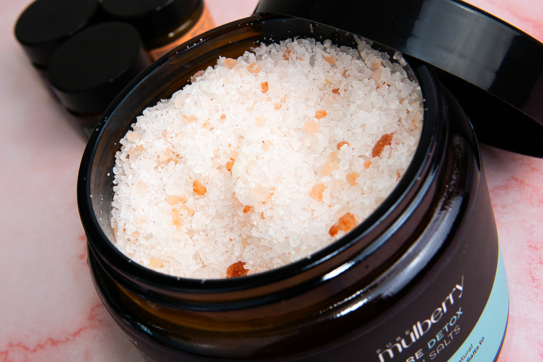 Close up opened amber jar with black lid detoxing white and pink  bath salts with essential oils 