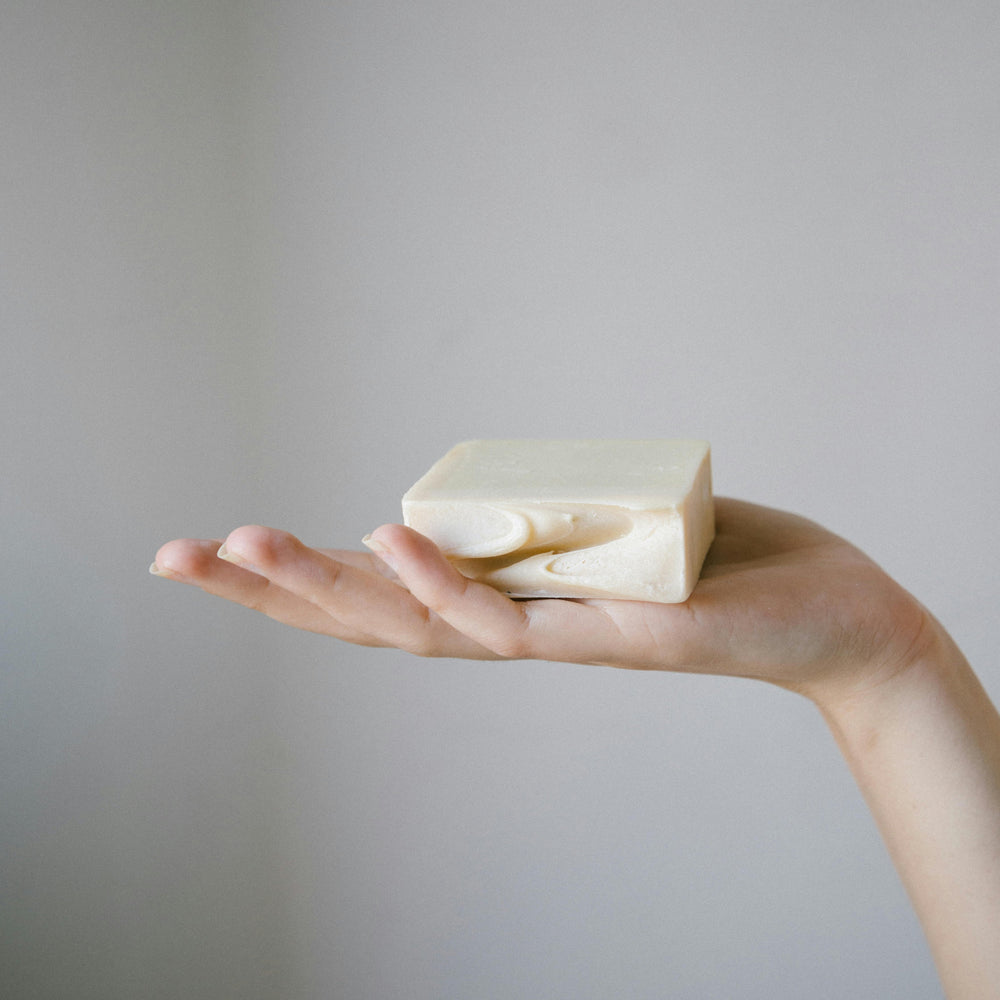 A hand holding a natural coloured soap