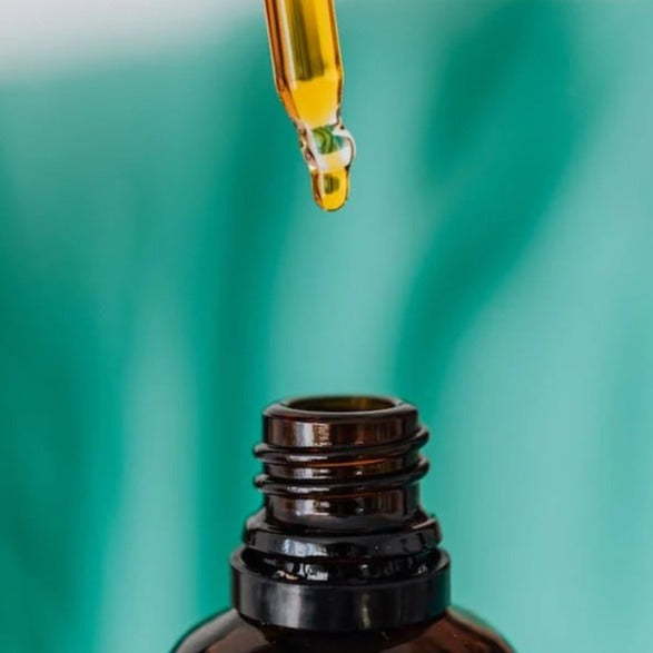 Close up image of face oil dropping into amber bottle