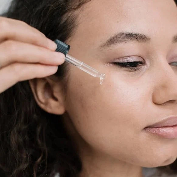 Lady dropping face oil onto cheek